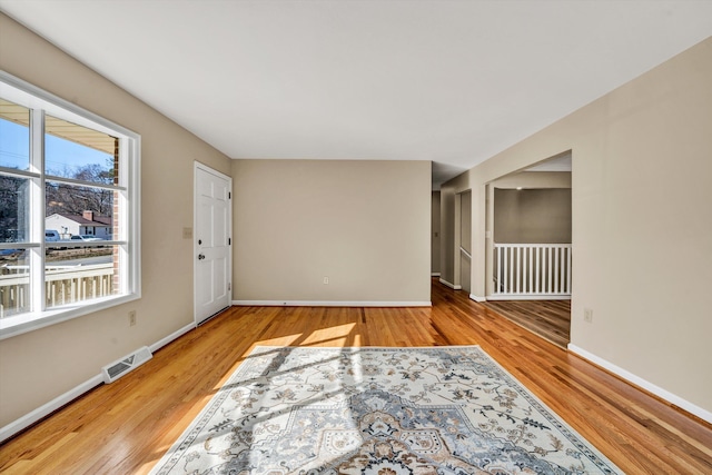 unfurnished room with wood finished floors, visible vents, and baseboards