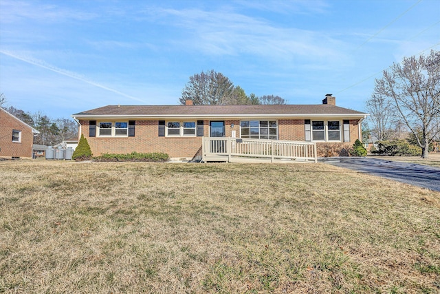 ranch-style house with a front yard, a chimney, and brick siding