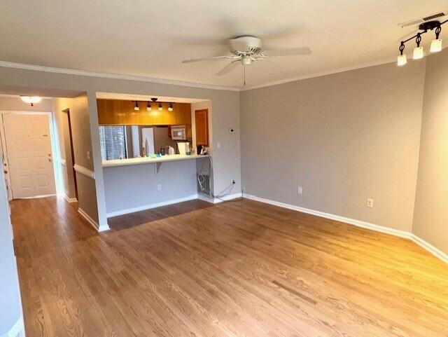 spare room with visible vents, baseboards, ceiling fan, wood finished floors, and crown molding