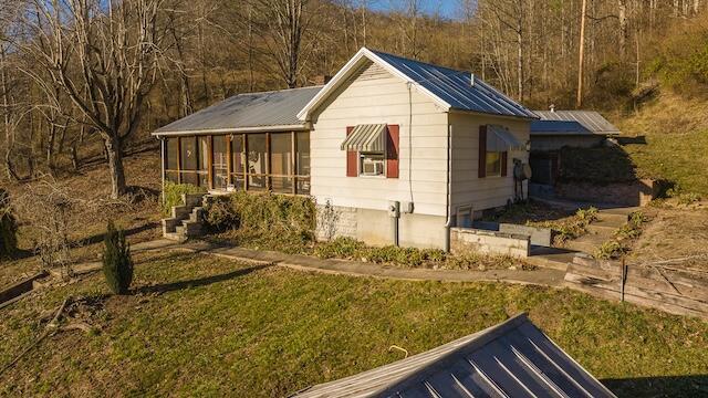 exterior space with a sunroom, a front lawn, and metal roof