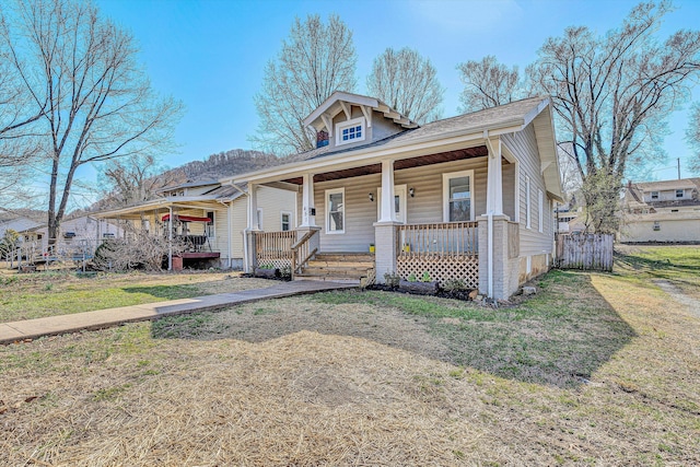 bungalow-style home featuring a porch, a front yard, and fence