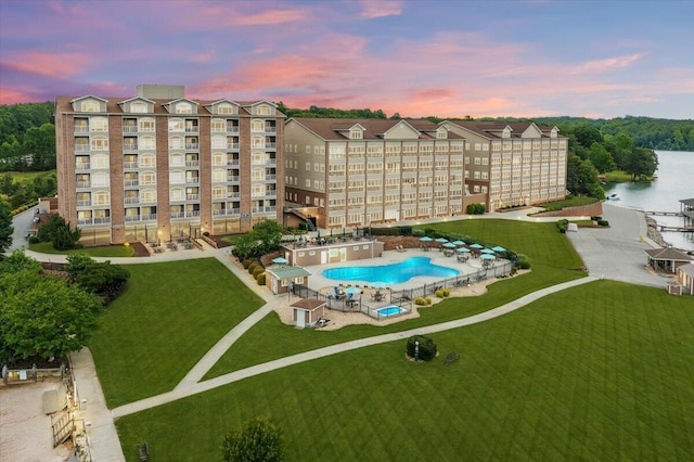 community pool featuring a water view, a patio, and a lawn