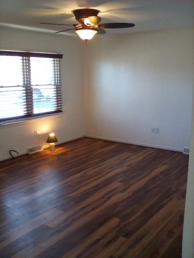 spare room featuring dark wood-type flooring and a ceiling fan