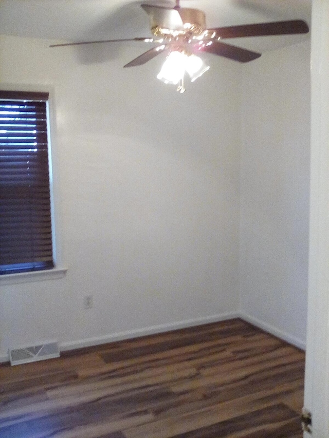 empty room with a ceiling fan, wood finished floors, visible vents, and baseboards