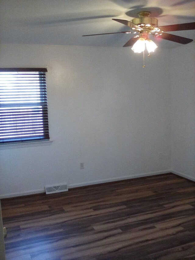 unfurnished room with a ceiling fan, wood finished floors, visible vents, and baseboards