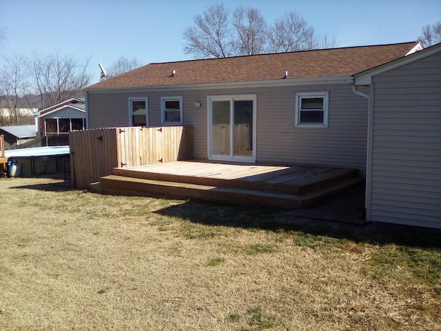 rear view of property featuring a lawn and a deck