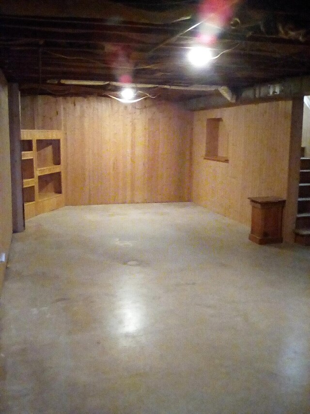 basement with carpet flooring and wooden walls