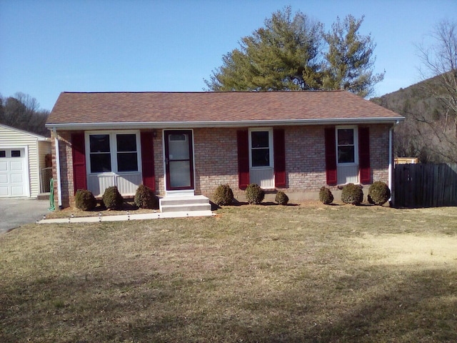 ranch-style house with roof with shingles, fence, an outdoor structure, a front lawn, and brick siding