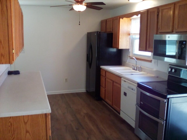 kitchen with a sink, a ceiling fan, appliances with stainless steel finishes, brown cabinets, and dark wood finished floors