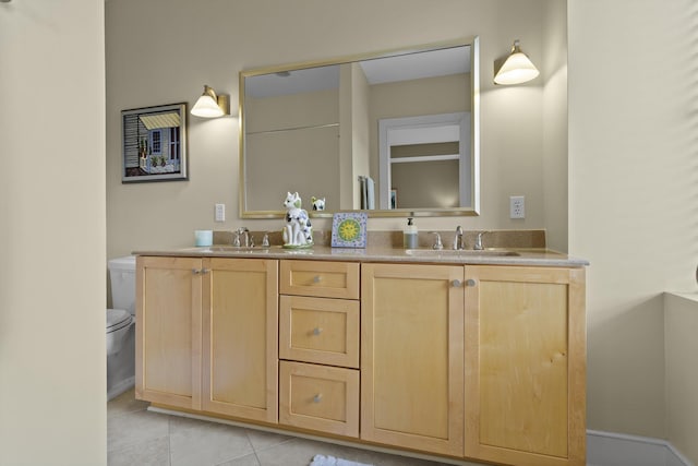 bathroom featuring toilet, double vanity, a sink, and tile patterned floors