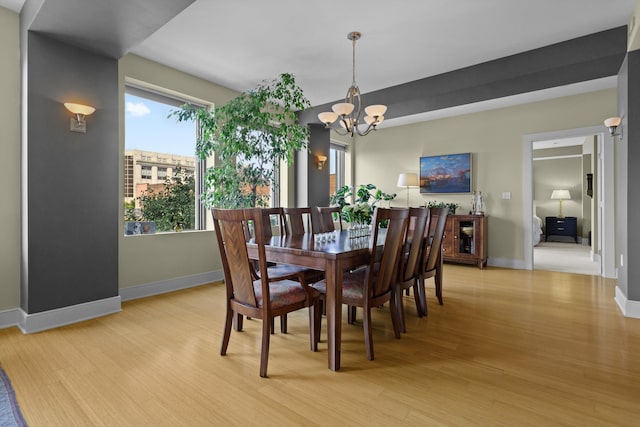 dining room with a chandelier, baseboards, and light wood-style floors