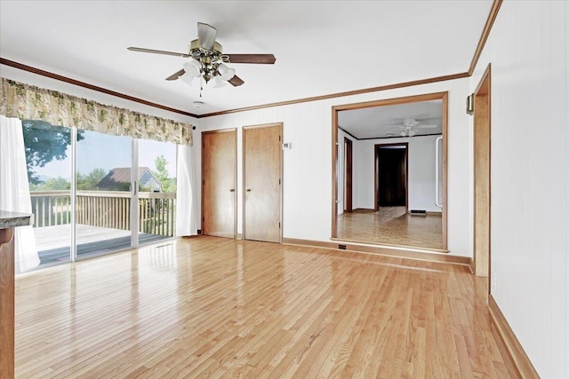 spare room featuring light wood-type flooring, baseboards, a ceiling fan, and crown molding