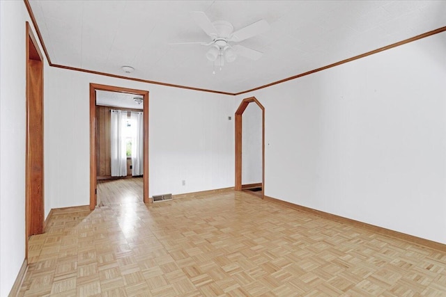 empty room featuring arched walkways, a ceiling fan, baseboards, visible vents, and crown molding