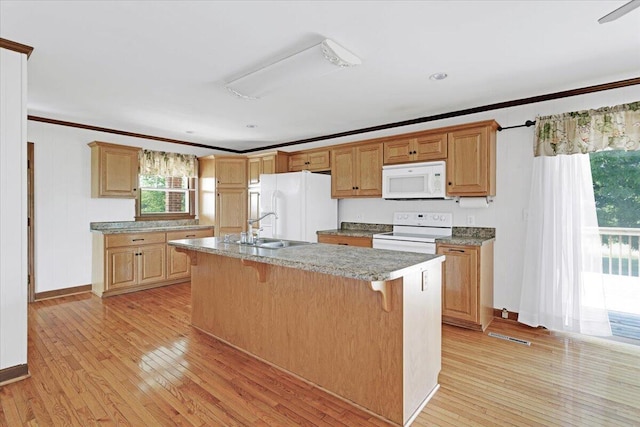 kitchen with white appliances, ornamental molding, light wood-style floors, and a sink