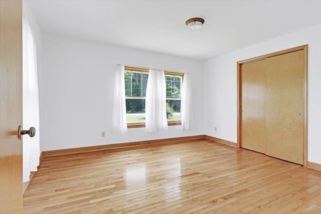 unfurnished bedroom featuring a closet, baseboards, and light wood finished floors