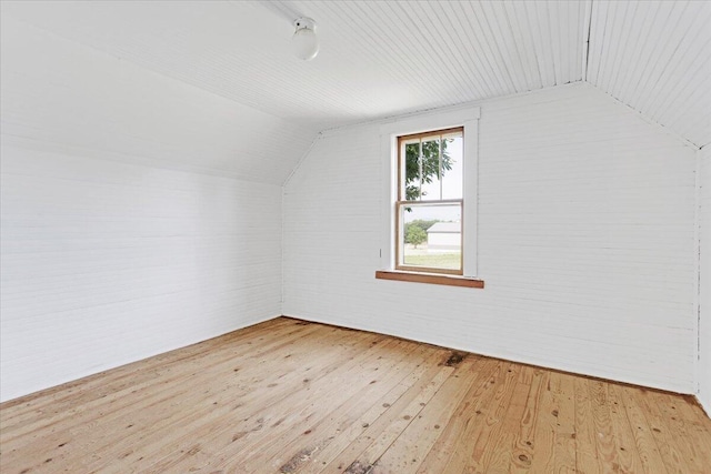 bonus room with vaulted ceiling, brick wall, and light wood-style flooring