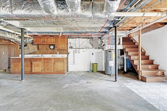 unfinished basement with concrete block wall, water heater, and stairs