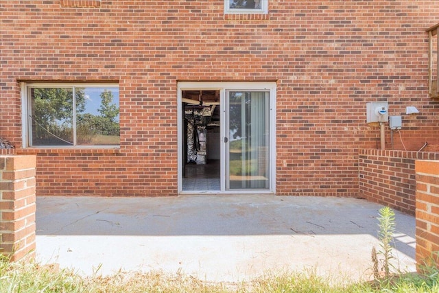 entrance to property featuring brick siding and a patio