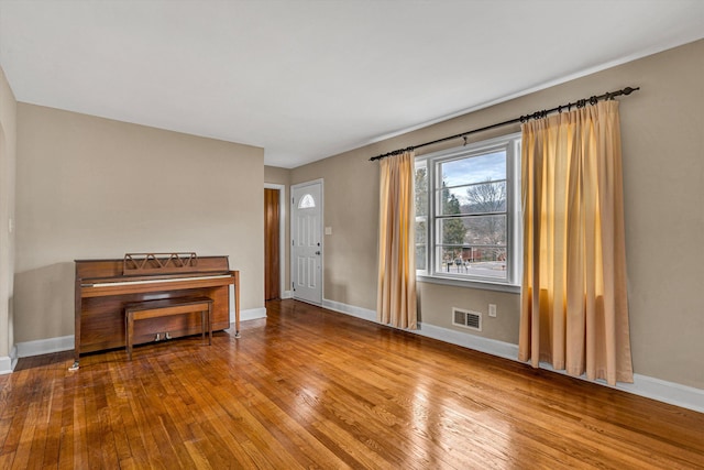 interior space featuring baseboards, visible vents, and hardwood / wood-style floors