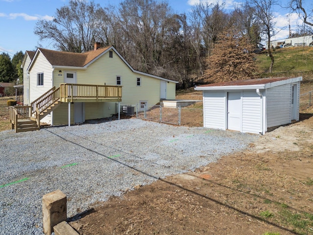 view of property exterior with central AC unit, a storage shed, an outdoor structure, a wooden deck, and a chimney