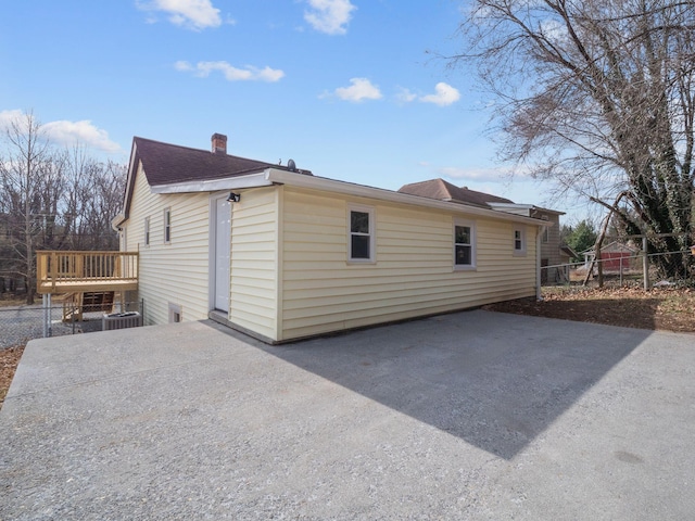 view of side of property with a patio, a chimney, fence, and driveway