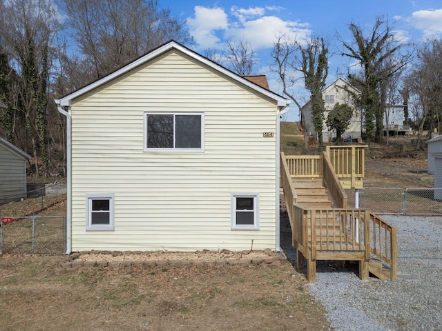 view of side of home featuring fence, a deck, and stairs