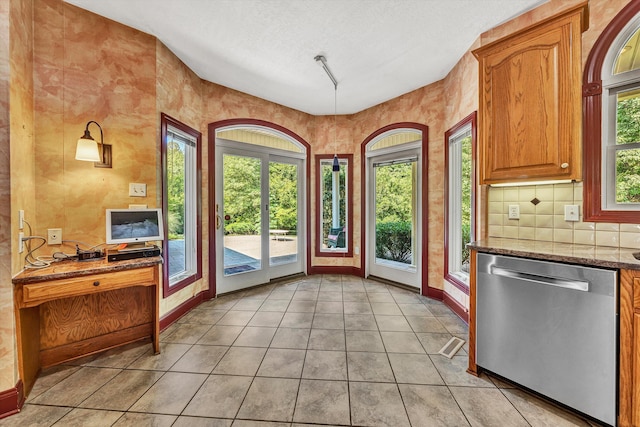 doorway with light tile patterned floors, a textured ceiling, and baseboards