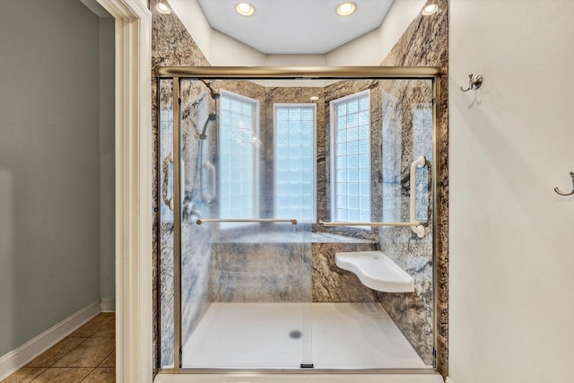 full bath featuring a stall shower, tile patterned flooring, and baseboards