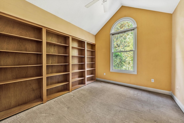 carpeted empty room with a wealth of natural light, visible vents, vaulted ceiling, and ceiling fan