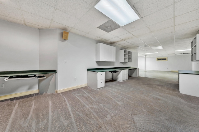 kitchen featuring a drop ceiling, carpet flooring, and white cabinetry