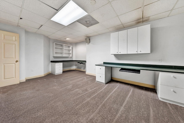 unfurnished office featuring carpet, baseboards, a drop ceiling, and built in study area