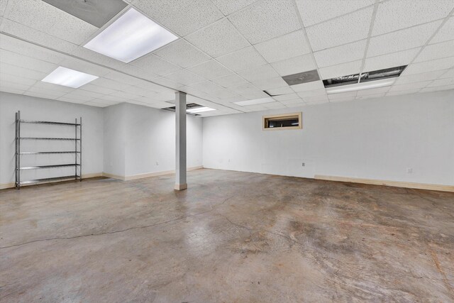 finished basement with a paneled ceiling and baseboards