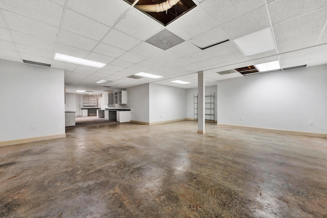 finished basement with a paneled ceiling and baseboards