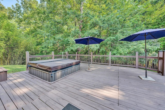 deck featuring a view of trees and a covered hot tub