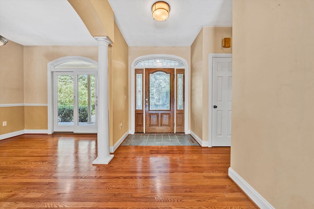 entryway with decorative columns, baseboards, and wood finished floors