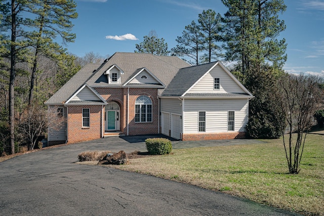 view of front facade with an attached garage, brick siding, aphalt driveway, and a front yard