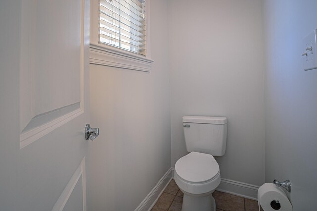 bathroom with toilet, baseboards, and tile patterned floors