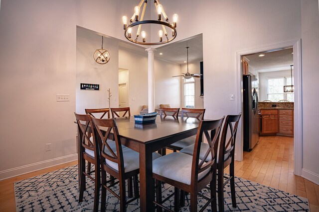 dining space with a healthy amount of sunlight, light wood-style flooring, baseboards, and ceiling fan with notable chandelier