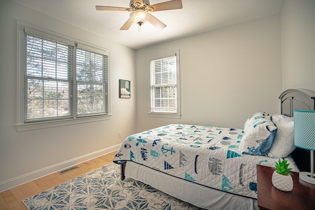 bedroom featuring baseboards, visible vents, ceiling fan, and wood finished floors