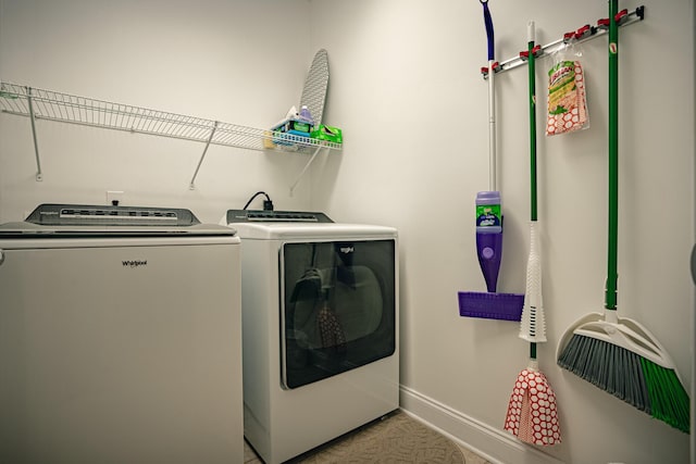 laundry area with laundry area, washing machine and dryer, and baseboards