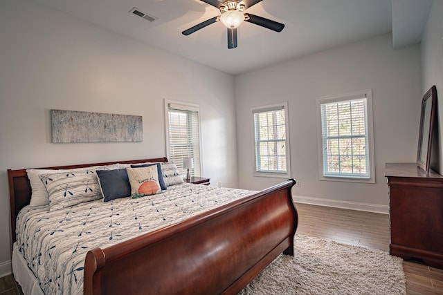 bedroom featuring a ceiling fan, dark wood-style flooring, visible vents, and baseboards