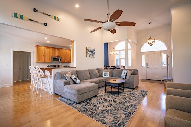 living area featuring light wood-type flooring, a high ceiling, crown molding, and recessed lighting