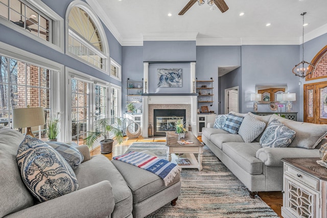 20 Waverly Ct, Moneta, VA 24121 - living room with ornamental molding, ceiling fan with notable chandelier, a high ceiling, wood finished floors, and a glass covered fireplace