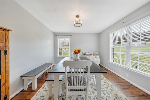 dining space with an inviting chandelier, wood finished floors, and baseboards