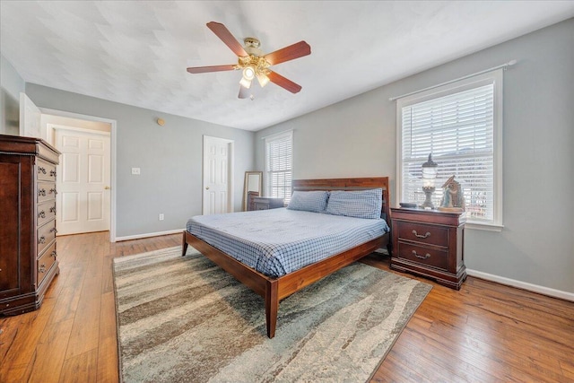 bedroom with a ceiling fan, hardwood / wood-style flooring, and baseboards