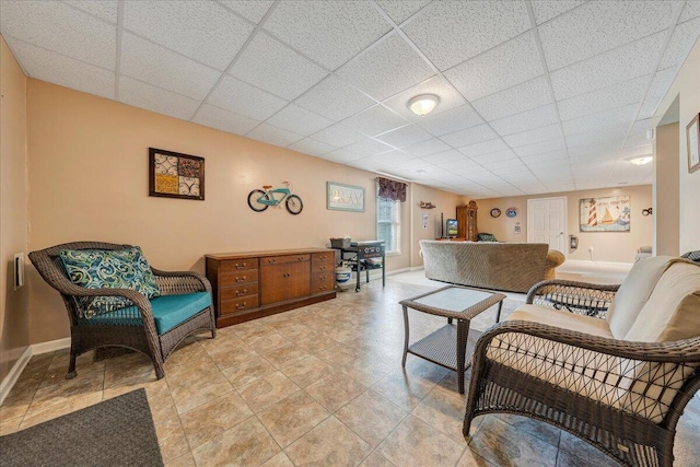 living area with baseboards and a drop ceiling