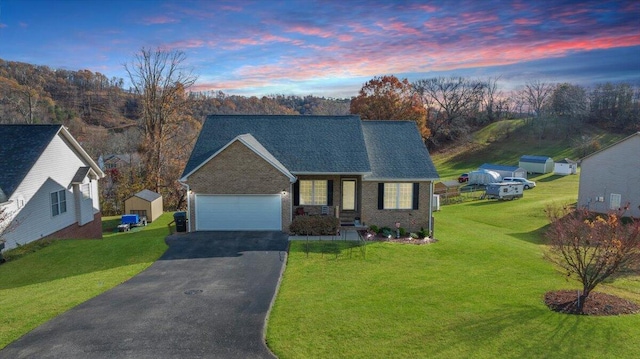 view of front of house featuring a garage, driveway, a front lawn, and brick siding