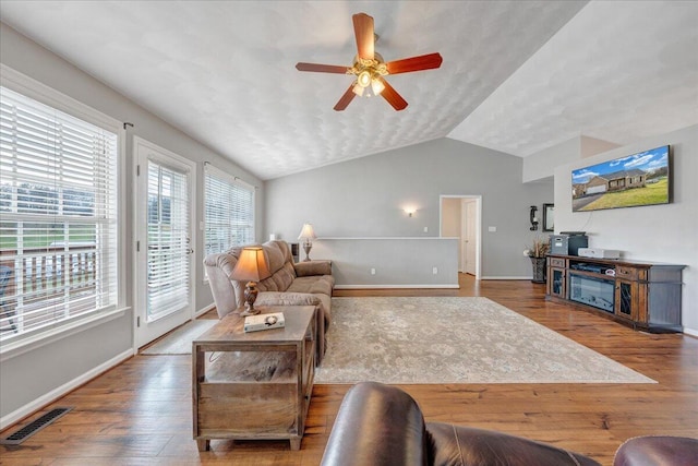 living room with baseboards, visible vents, a ceiling fan, hardwood / wood-style flooring, and vaulted ceiling