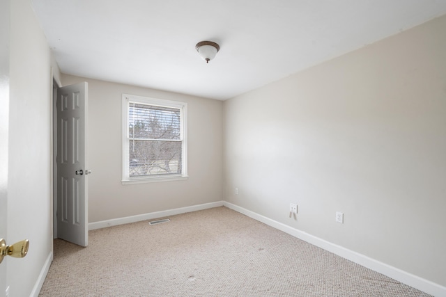 empty room with carpet floors, visible vents, and baseboards