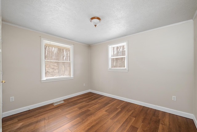 spare room with a textured ceiling, visible vents, baseboards, wood-type flooring, and crown molding